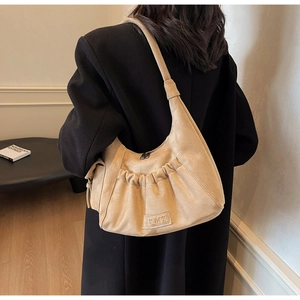 Detail of beige suede hobo bag with pleated front pocket and LKMX leather brand tag