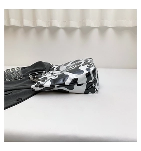 Detail of glossy cow print tote bag featuring stylish silver metal ring handles