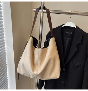 Detailed close-up of beige suede tote bag with brown leather strap and gold buckle