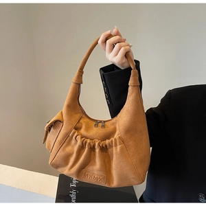 Close-up of brown suede hobo bag with pleated pocket and embossed MKMX logo detail
