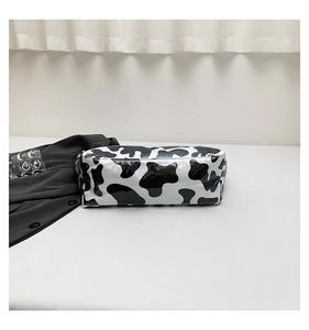 Detail of waterproof cow print makeup bag with a black ribbon handle on a white desk