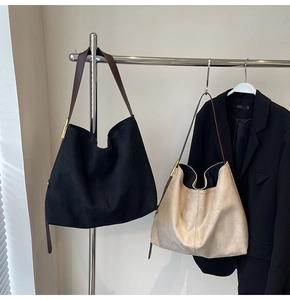 Detail of minimalist suede hobo bags in black and beige with slim leather straps
