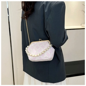 Detail of white textured crossbody bag with pearl handle and golden chain on a model