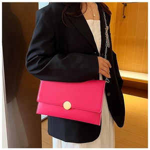 Dettaglio della borsa fucsia a bustina con fibbia dorata e tracolla a catena