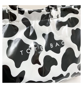 Close-up of glossy cow print tote bag detail showing handles and Tote Bag lettering