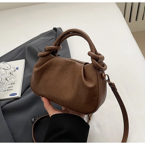 Dettaglio della borsa a dumpling marrone pieghettata con manico annodato e logo