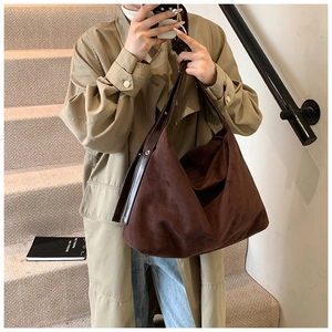 Side view of large dark brown suede tote bag with shiny leather strap on shoulder