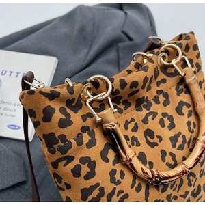 Dettaglio della borsa leopardata con manico in bambù e tracolla sottile marrone