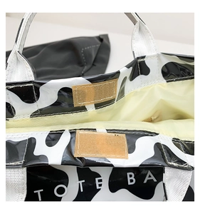 Detail view of the velcro closure and white strap on the cow print tote bag