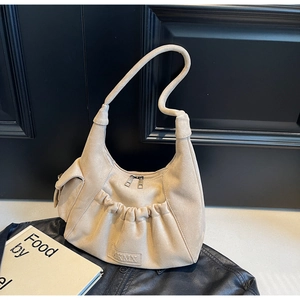 Detail of beige suede hobo bag with pleated pocket texture on a black leather jacket