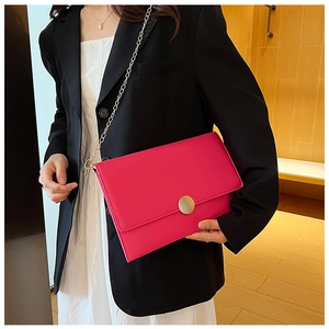 Dettaglio dell'elegante borsa a bustina fucsia con catena dorata e fibbia circolare