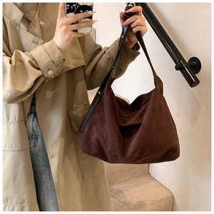 Detail of a dark brown suede tote bag with smooth leather straps shown in a lifestyle mirror shot