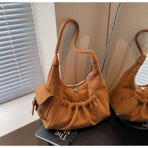 Detailed view of brown suede shoulder bag featuring soft pleats and side flap pocket