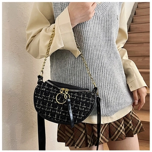 Close-up of black and white tweed saddle bag with gold chain and ring zipper detail