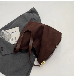 Detail of dark brown suede hobo bag with smooth leather strap and gold metal hardware