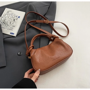 Dettaglio borsa marrone arricciata con manico a nodo e logo di moda in rilievo