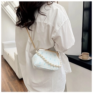 Detail of blue quilted handbag with large pearl handle and gold chain strap on a model