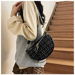Model wearing a black and white tweed saddle waist bag with gold chain and leather strap