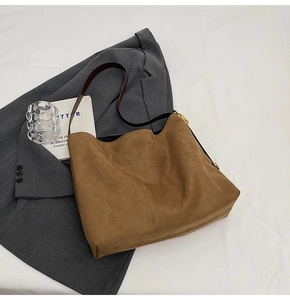 Close-up of caramel suede tote bag with brown leather strap and gold metal buckle