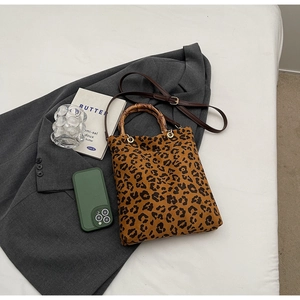 Dettaglio borsa leopardata con manico in bambù e tracolla in pelle marrone regolabile
