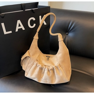 Detail of beige suede tote bag with unique wave handle and pleated pocket design