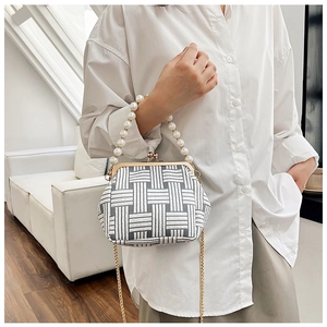 Detail of grey geometric woven handbag with large pearl handle and gold chain strap
