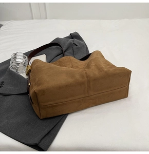 Close-up of large dark brown suede tote bag with metal buckle and wide shoulder strap