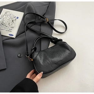 Dettaglio borsa nera in pelle PU plissettata con logo stampato e manico con nodo