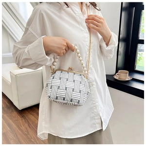 Detailed view of women's tweed handbag with faux pearl handle and gold chain strap