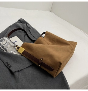 Detailed close-up of brown suede hobo bag with dark leather strap and gold metal buckle