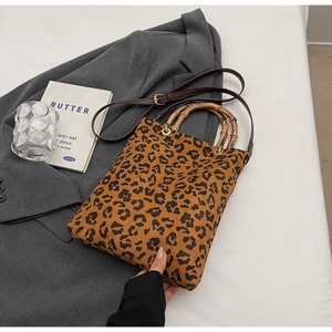 Dettaglio della borsa leopardata con manico in bambù e tracolla marrone su un blazer