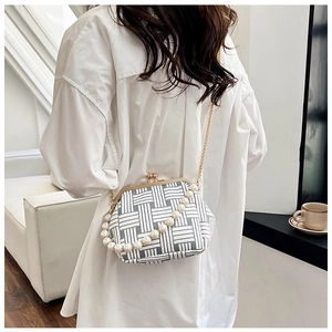 Detailed view of geometric weave clutch bag with faux pearl handle and metal clasp