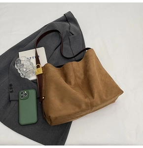 Close-up of brown suede bucket bag texture with leather strap and metal buckle detail