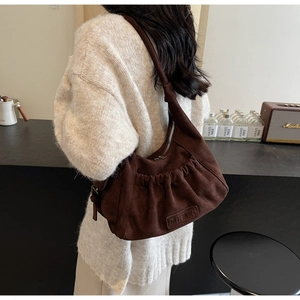 Detail of dark brown suede hobo bag with pleated texture and leather brand label