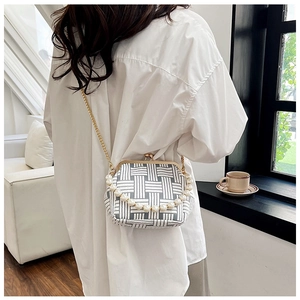 Detail view of woven mini crossbody bag with pearl handle and golden clasp closure
