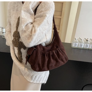 Detail of coffee suede tote bag with pleated texture and embossed MKMX logo patch