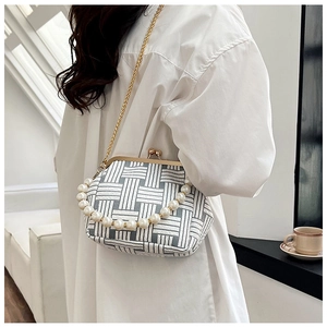 Detail of woven clutch bag with large pearl handle and gold chain strap on model