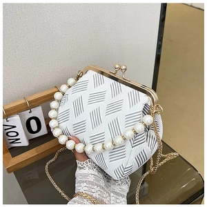 Detail of vintage frame bag with pearl handle, gold chain and striped pattern