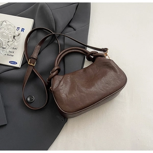 Détail de la poignée nouée et de la texture du cuir PU sur un sac marron foncé