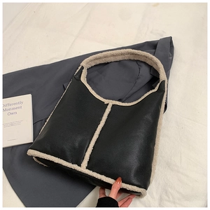 Dettaglio della borsa hobo in pelle nera con rifiniture in ecopelliccia crema e texture