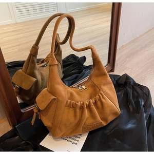 Detail of brown suede tote bag featuring unique wavy handle and pleated design