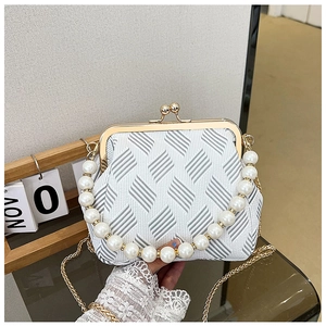 Detail of elegant pearl handle and vintage gold metal frame on a textured clutch bag