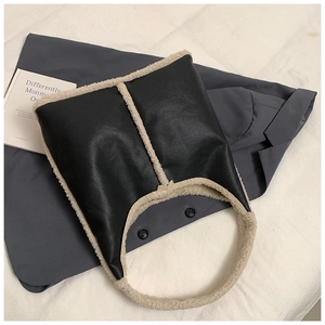 Dettaglio della borsa tote nera in ecopelle con bordo in shearling beige e trama martellata