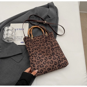 Dettaglio della borsa tote leopardata vintage con manico in bambù naturale e tracolla in pelle