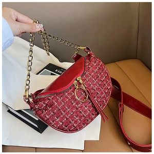 Detail of red saddle bag with tweed texture, gold chain handle and leather shoulder strap