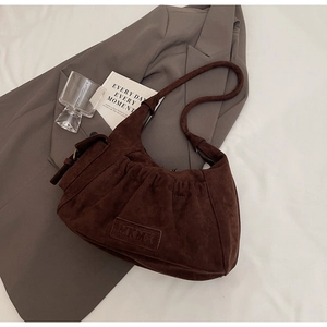Close-up of dark brown suede tote bag featuring pleated detail and MKMX leather label