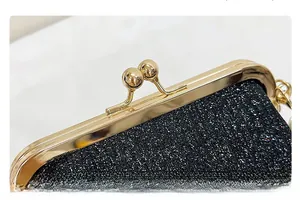 Detailed view of black glitter clutch bag with golden metal frame and kiss lock closure