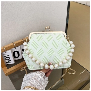 Detail of light green kiss-lock bag with pearl handle and woven texture