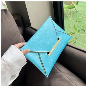 Détail d'une pochette enveloppe bleu clair avec paillettes et bordure métallique dorée