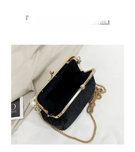 Macro view of a black glitter clutch bag with gold frame and large interior space
